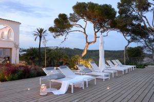 una fila de tumbonas blancas en una terraza de madera en Villa Casa del Mar, en Sant Pere de Ribes