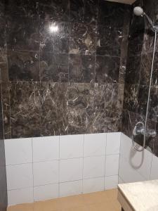 a bathroom with a shower with black and white tiles at Fratini's Hotel Labuan in Labuan