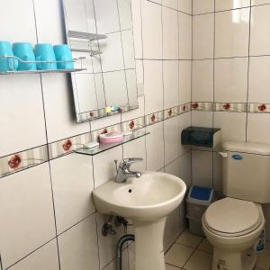 ein Badezimmer mit einem Waschbecken, einem WC und einem Spiegel in der Unterkunft Jinsha Vanilla Homestay in Insel Nangan