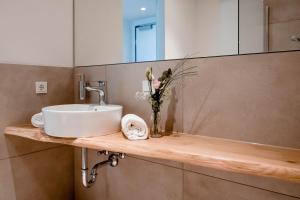 a bathroom with a sink and a vase of flowers on a counter at Zeitlos Boutiquehotel in Limburg an der Lahn +8 photos