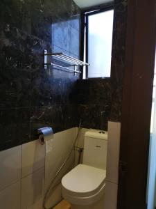 a bathroom with a toilet and a window at Fratini's Hotel Labuan in Labuan