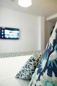 a bedroom with a couch with pillows and a tv at Hotel Avenida Playa in Zahara de los Atunes