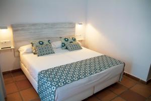 a bedroom with a white bed with blue pillows at Hotel Avenida Playa in Zahara de los Atunes