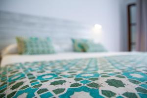 a bed with a blue and white comforter on it at Hotel Avenida Playa in Zahara de los Atunes