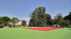a tennis court with a net on a green field at Chambres d'hotes de Pouzelande in Notre-Dame-de-Sanilhac