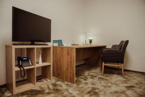 biurko z telewizorem, krzesłem i telefonem w obiekcie Hotel Aréna w Koszycach