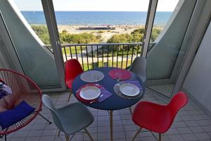 einen Balkon mit Tisch und Stühlen sowie Strand in der Unterkunft Studio de 33 m2, vue et bord de mer, parking in La Grande-Motte