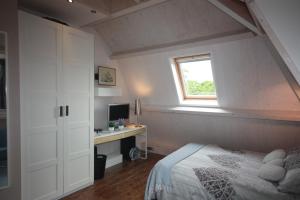 a bedroom with a bed and a desk and a window at De Pimpelmees in The Hague