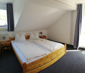 Un dormitorio con una gran cama de madera con sábanas blancas. en Pension "Dorfkrug", en Winterberg