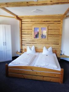 Cama grande en habitación con pared de madera en Pension "Dorfkrug" en Winterberg