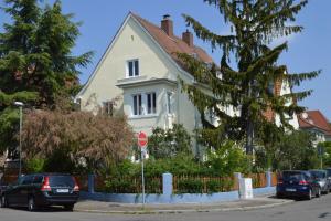 Una casa blanca con autos estacionados frente a ella. en Emmas en Neustadt an der Weinstraße