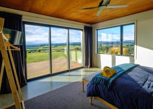 1 dormitorio con cama y ventana grande en Fiordland Eco-Retreat -- Panoramic Views -- Hot Tub, en Te Anau