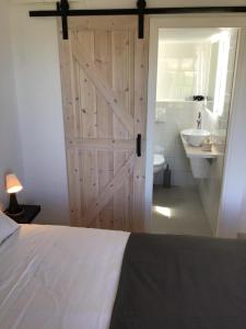 a bedroom with a sliding barn door and a bathroom at The Olive Garden Apartments in Gouves