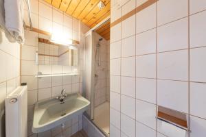 a white tiled bathroom with a sink and a shower at Alpenhof in Ramsau am Dachstein