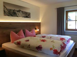 Schlafzimmer mit einem Bett mit roten und weißen Kissen in der Unterkunft Haus Hochwies in Bolsterlang