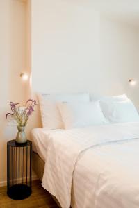 una cama con sábanas blancas y un jarrón de flores sobre una mesa en Heirloom Hotels - The Librarian en Ghent