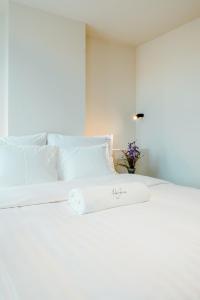 a white bed with white pillows and a vase of flowers at The Librarian by Domani Hotels in Ghent