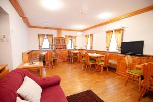 ein Wohnzimmer mit Tischen, Stühlen und einem TV in der Unterkunft Guest house Vila Korošec in Bovec