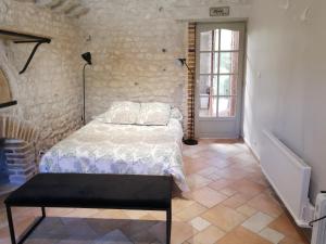 a bedroom with a bed and a stone wall at Forest Farm in Bois-Jérôme-Saint-Ouen