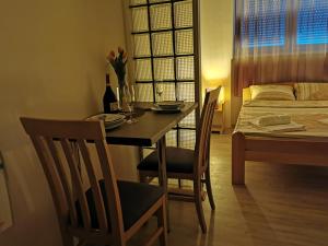 a dining room table with two chairs and a bed at Apartments Take a Break Novi Sad in Novi Sad