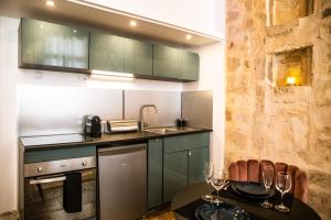 モンペリエにあるSuite romantique avec Jacuzzi - Hypercentre, Place Jean Jaurèsのキッチン(緑のキャビネット、ワイングラス付きのテーブル付) +6枚の写真