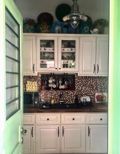 a kitchen with white cabinets and a tile wall at The house in the port in Korissia +38 photos