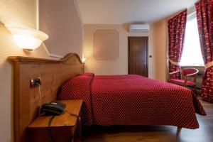 a bedroom with a bed with a phone on a table at Hotel Elena in Saint Vincent