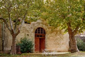 a building with a wooden door and two trees at Domaine Des Agnelles in Villedaigne