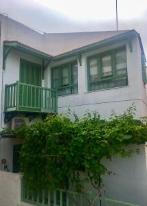 Una casa blanca con un balcón verde. en The house in the port, en Korissia