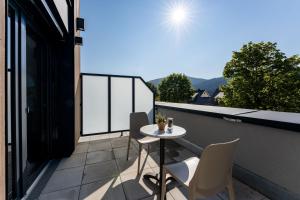 een patio met een tafel en stoelen op een balkon bij coucou hotel & kuckucks-stube (Titisee) in Titisee-Neustadt