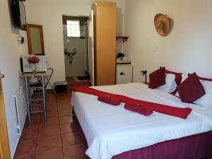 um quarto com uma grande cama branca com almofadas vermelhas em 1010 Clifton bnb em Centurion