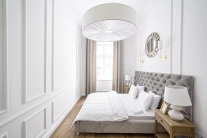 biała sypialnia z łóżkiem i dużym żyrandolem w obiekcie Apartament Golden Place w Krakowie
