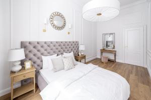 biała sypialnia z dużym łóżkiem i lustrem w obiekcie Apartament Golden Place w Krakowie