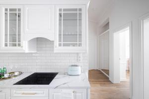 una cocina blanca con armarios blancos y fregadero en Apartament Golden Place en Cracovia