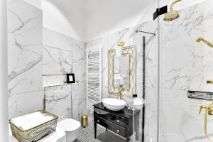 Łazienka z marmurowymi ścianami, umywalką i lustrem w obiekcie Apartament Golden Place w Krakowie