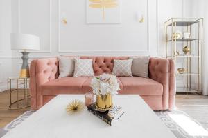 a living room with a pink couch and a table at Apartament Golden Place in Kraków