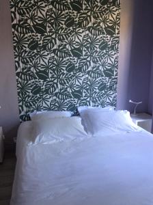 1 dormitorio con cama blanca y pared en blanco y negro en Les Cabanes de Do en Le Mans