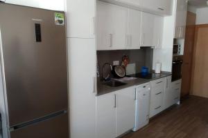 a kitchen with white cabinets and a stainless steel refrigerator at Apartamento en primera línea de mar en Vilafortuny, Cambrils in Cambrils