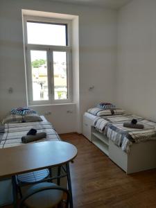 two beds in a room with a table and a window at Apartments Todorovic in Pula