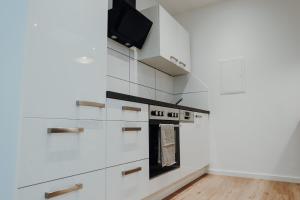 a kitchen with white cabinets and a tv on the wall at Ferienwohnung Alte Wäscherei in Kitzingen