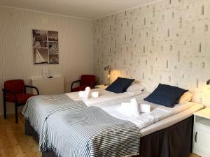 two beds in a room with two red chairs at Villa Frideborg in Henån