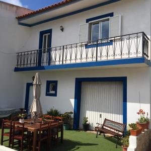 a blue and white house with a table and a balcony at Carrapateira Lodge in Carrapateira