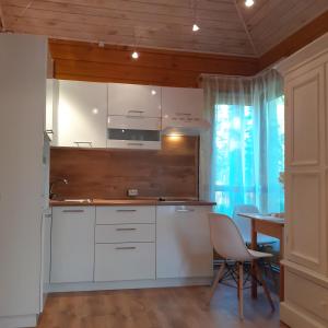 eine Küche mit weißen Schränken und einem Tisch mit Stühlen in der Unterkunft Zīlīšu holiday house in Jūrmala