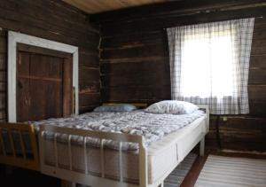 Cama en habitación de madera con ventana en Löydön Kartano Camping en Ristiina