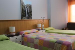 a bedroom with two beds with green and colorful blankets at Albergue Turístico Silleda in Silleda