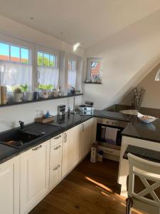 a kitchen with white cabinets and black counter tops at Haus Selma in Zingst