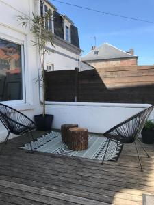 a patio with a bench and a tree stump at Les 2 C’ in Cayeux-sur-Mer