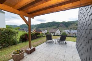 a patio with two chairs and a wooden pergola at Ferienwohnungen Schorn in Burg (an der Mosel)