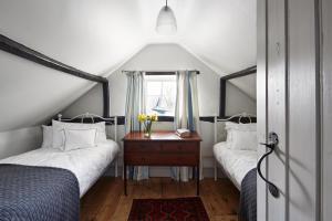 a attic bedroom with two beds and a window at Dog Cottage in Little Barningham