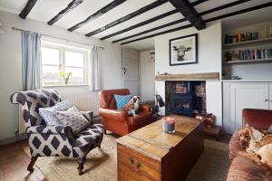 a living room with two chairs and a fireplace at Dog Cottage in Little Barningham